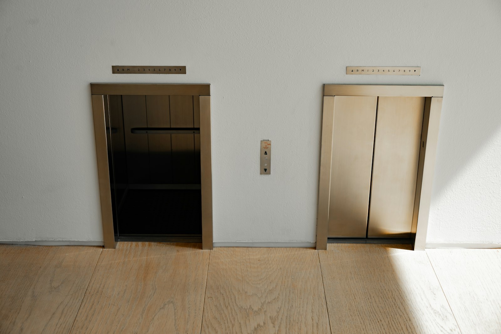 Stainless steel elevator doors with illuminated floor indicator panel above